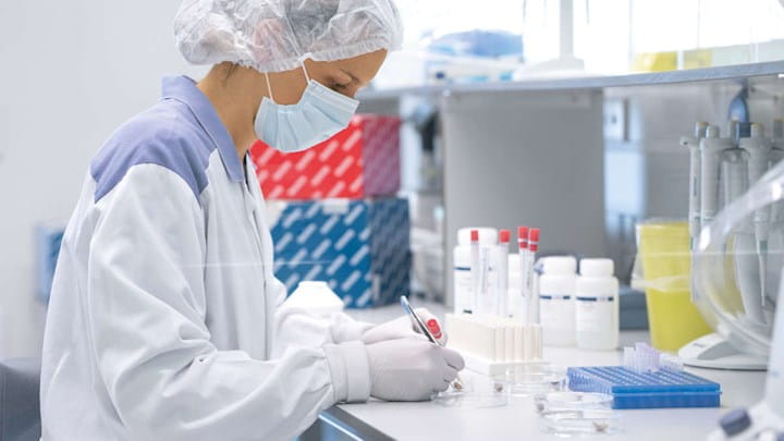 A woman in protective clothing working in a lab